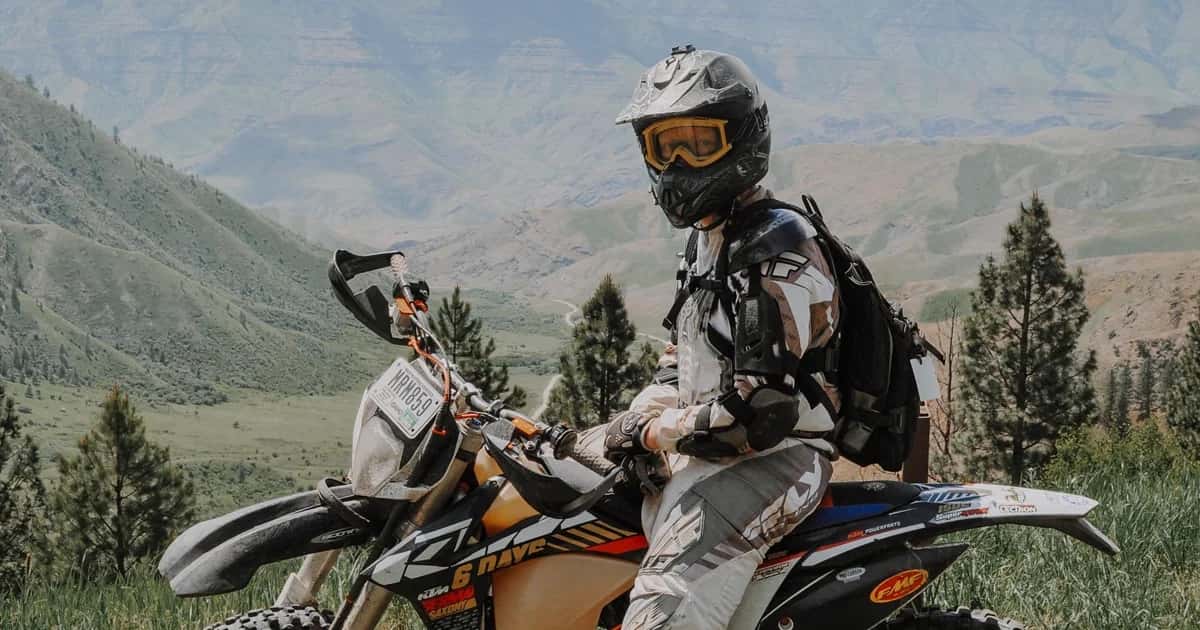 Motociclista com mochila em trilha de montanha com vista