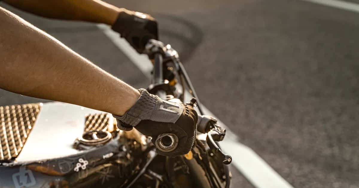 Mãos de motociclista com luvas no guidão em movimento
