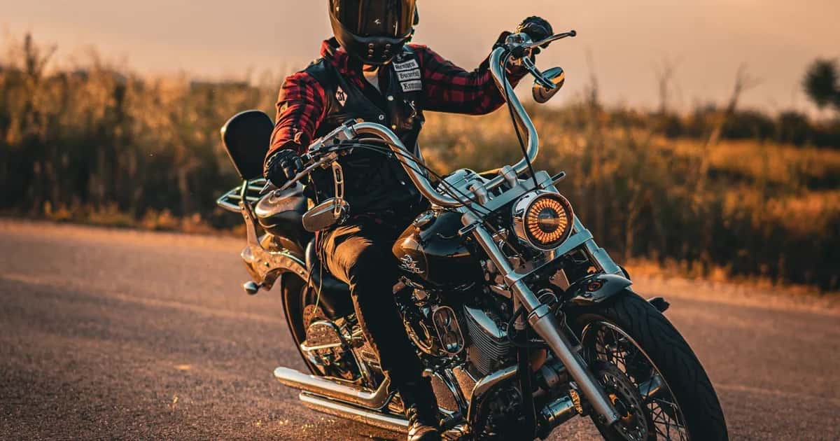 Motociclista rodando em estrada aberta ao pôr do sol dourado