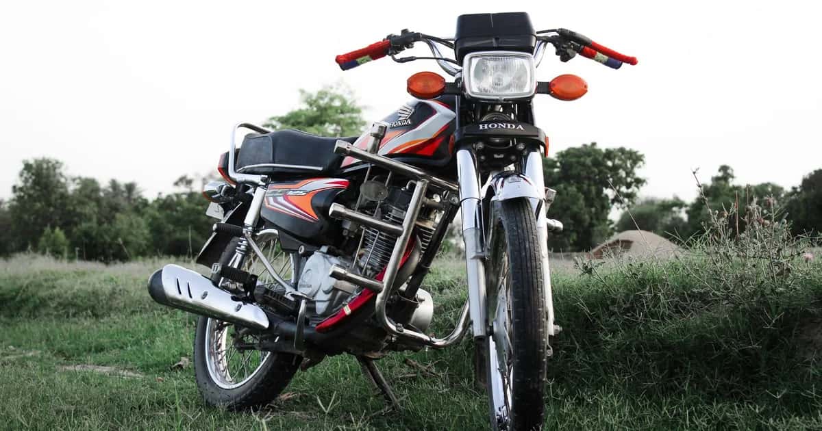 Moto de entrada estilo CG estacionada em área aberta, vista de frente em ângulo baixo