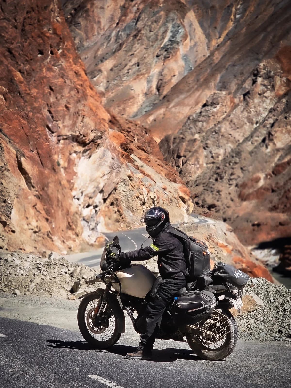 Motociclista cruzando paisagem árida com bagagem
