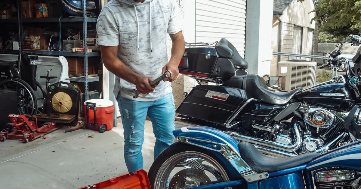 Homem trabalhando em moto em garagem cercado de ferramentas