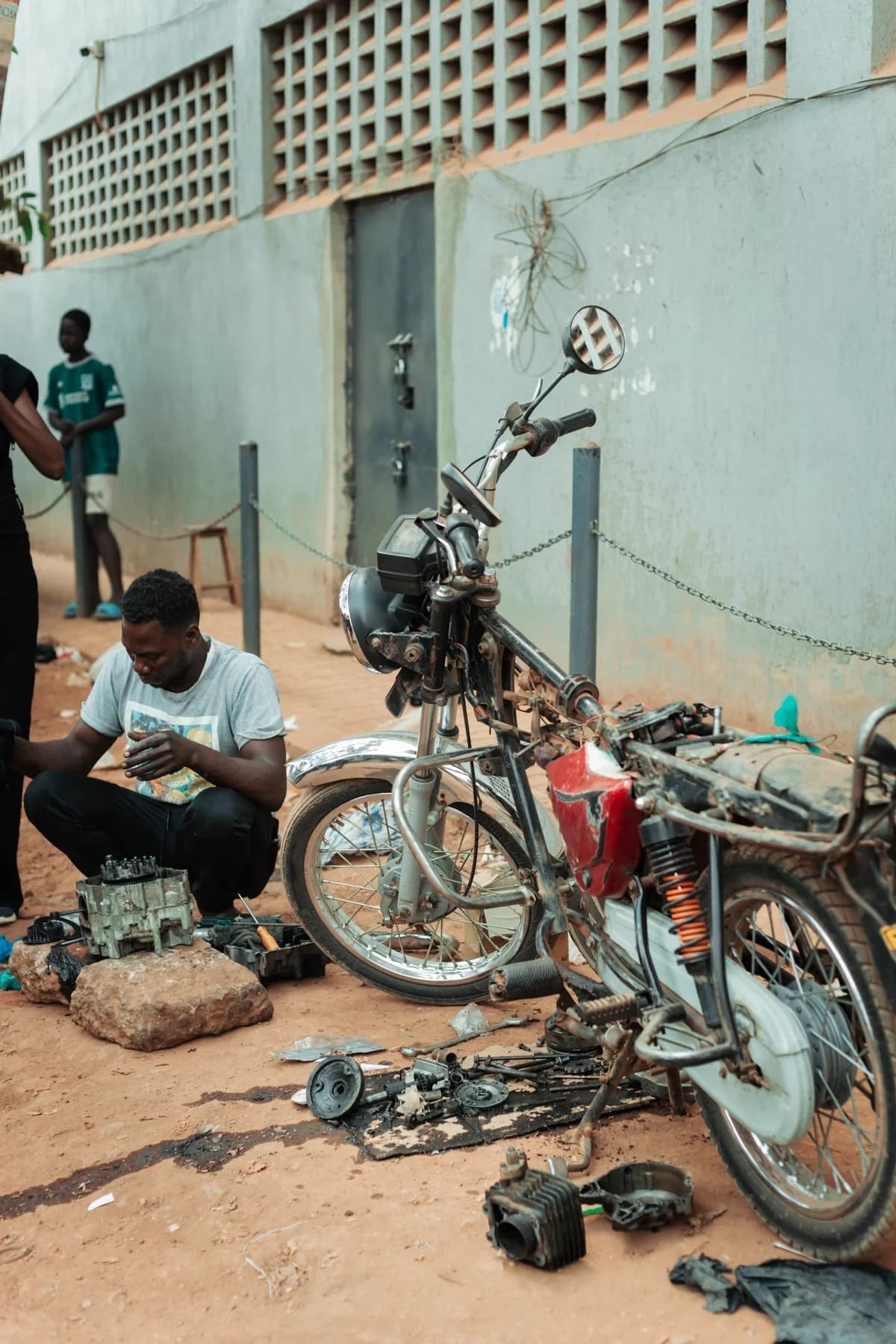 Mecânico jovem reparando moto em rua de terra durante o dia