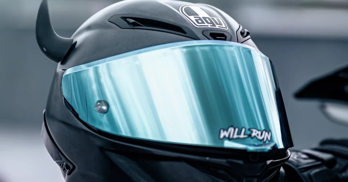 Capacete integral preto com viseira refletiva sobre a moto, em close