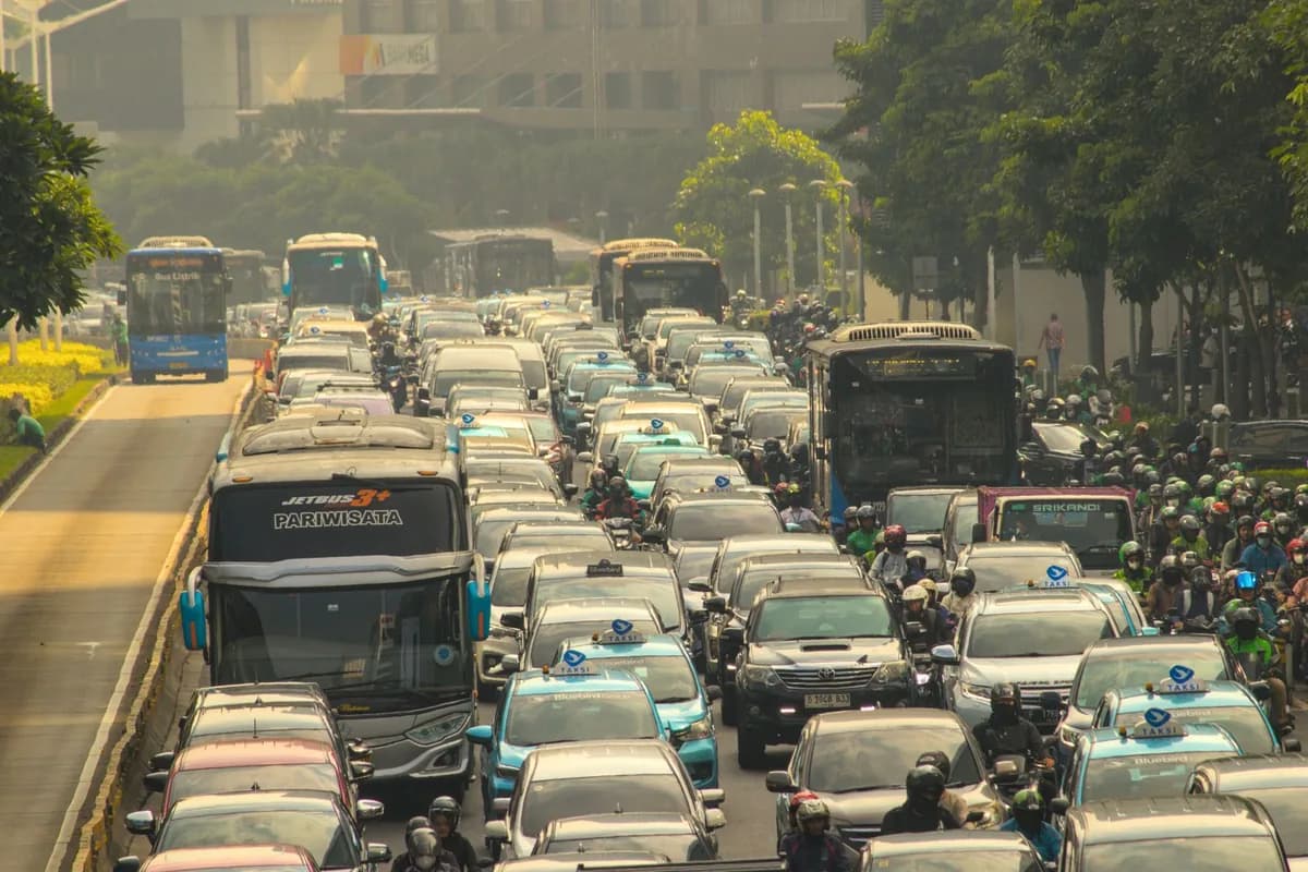 Congestionamento urbano com carros, ônibus e um bloco de motociclistas espremidos na lateral da via