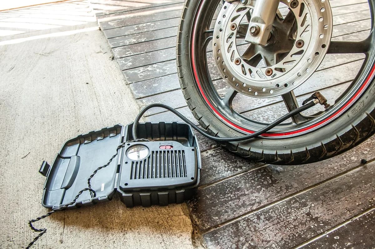 Compressor portátil com manômetro conectado à válvula do pneu dianteiro de uma moto