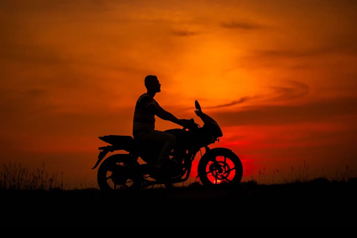 Silhueta de motociclista ao pôr do sol laranja