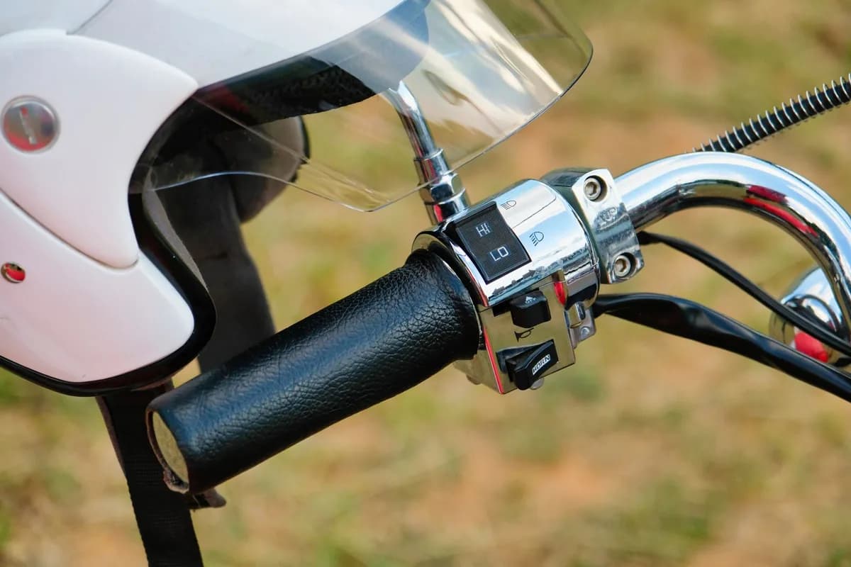 Capacete usado apoiado no guidão de uma moto, com o forro e a cinta jugular visíveis