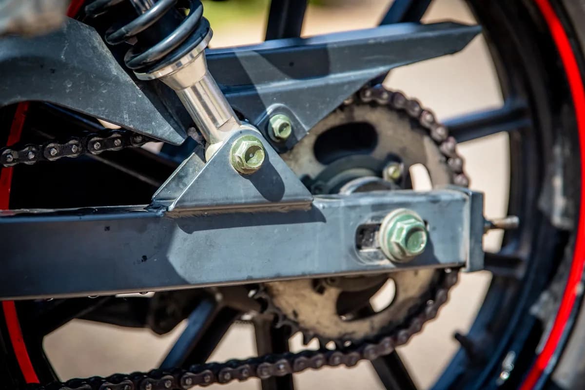 Close da corrente, da coroa e do esticador na balança traseira de uma moto