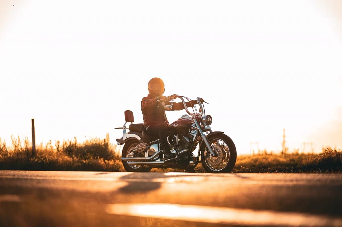 Motociclista ao pôr do sol em estrada aberta