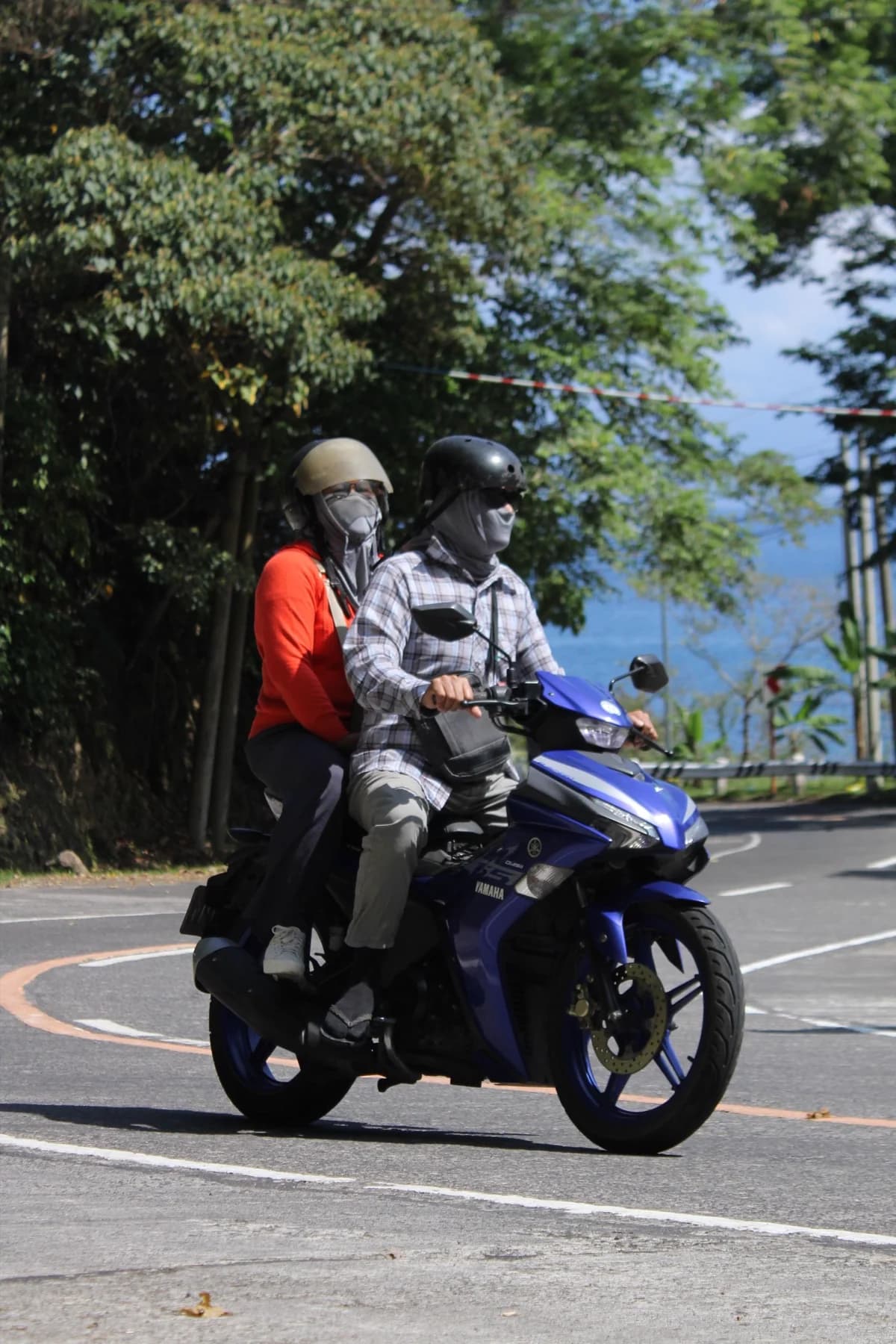 Casal de moto em estrada sinuosa de dia