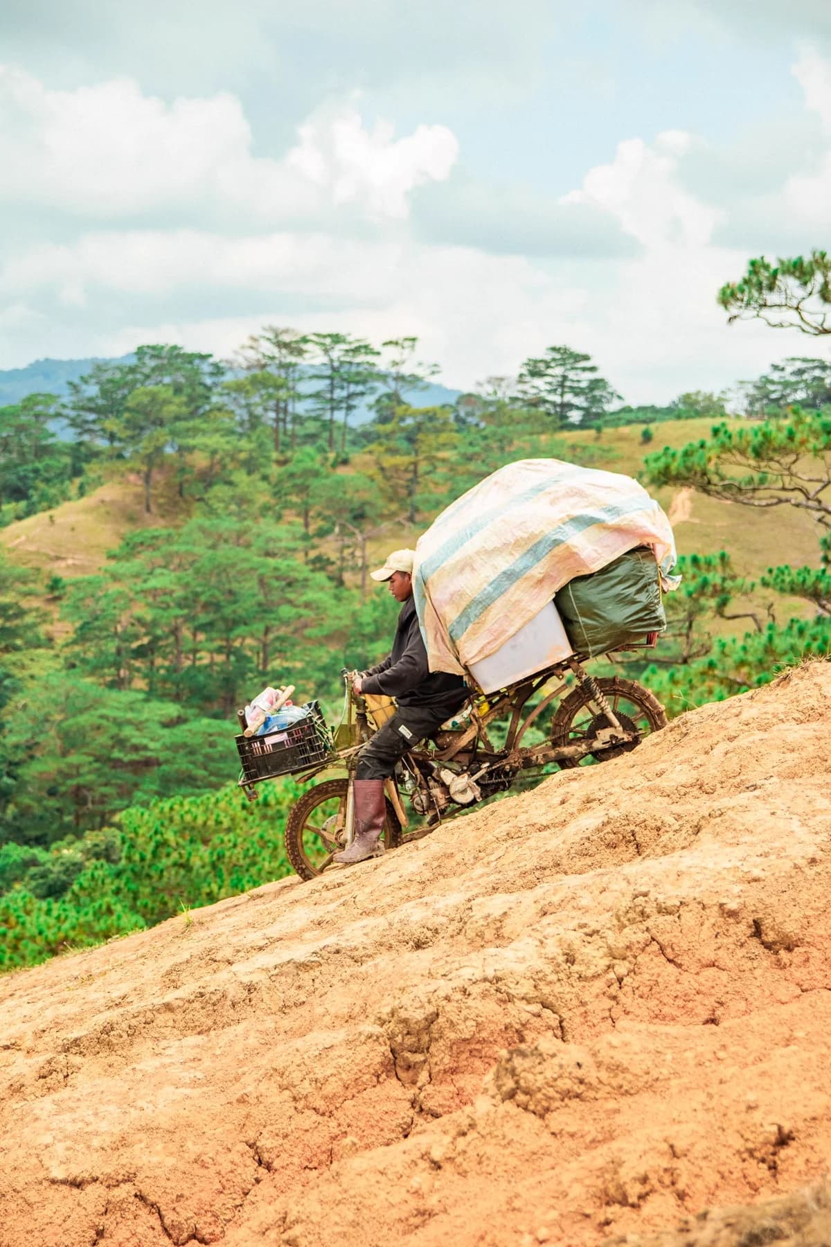 Moto carregada subindo ladeira íngreme em estrada de terra