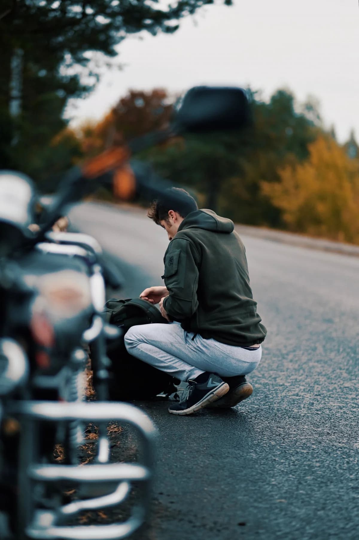 Motociclista ajustando equipamento ao lado da moto na estrada
