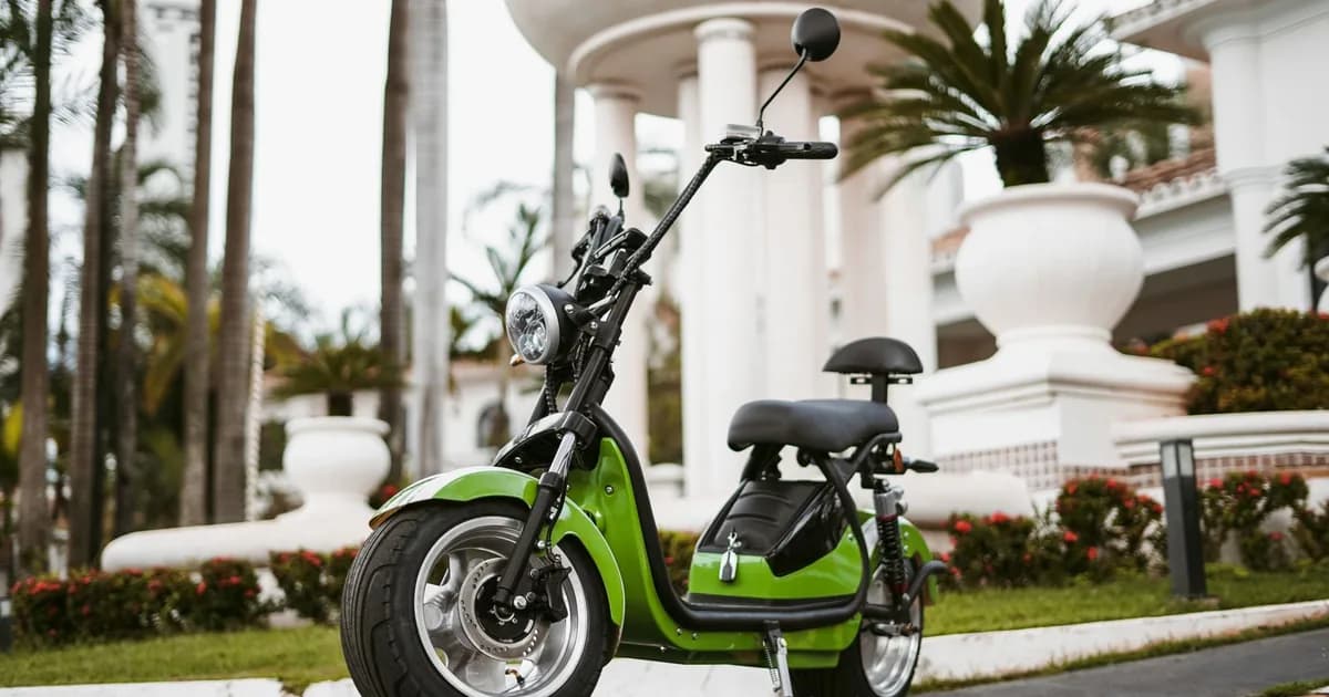 Scooter elétrica verde de pneus largos estacionada em área externa, sem placa