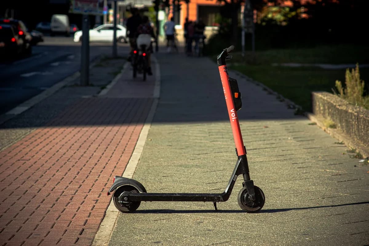 Patinete elétrico compartilhado estacionado em calçada urbana ensolarada