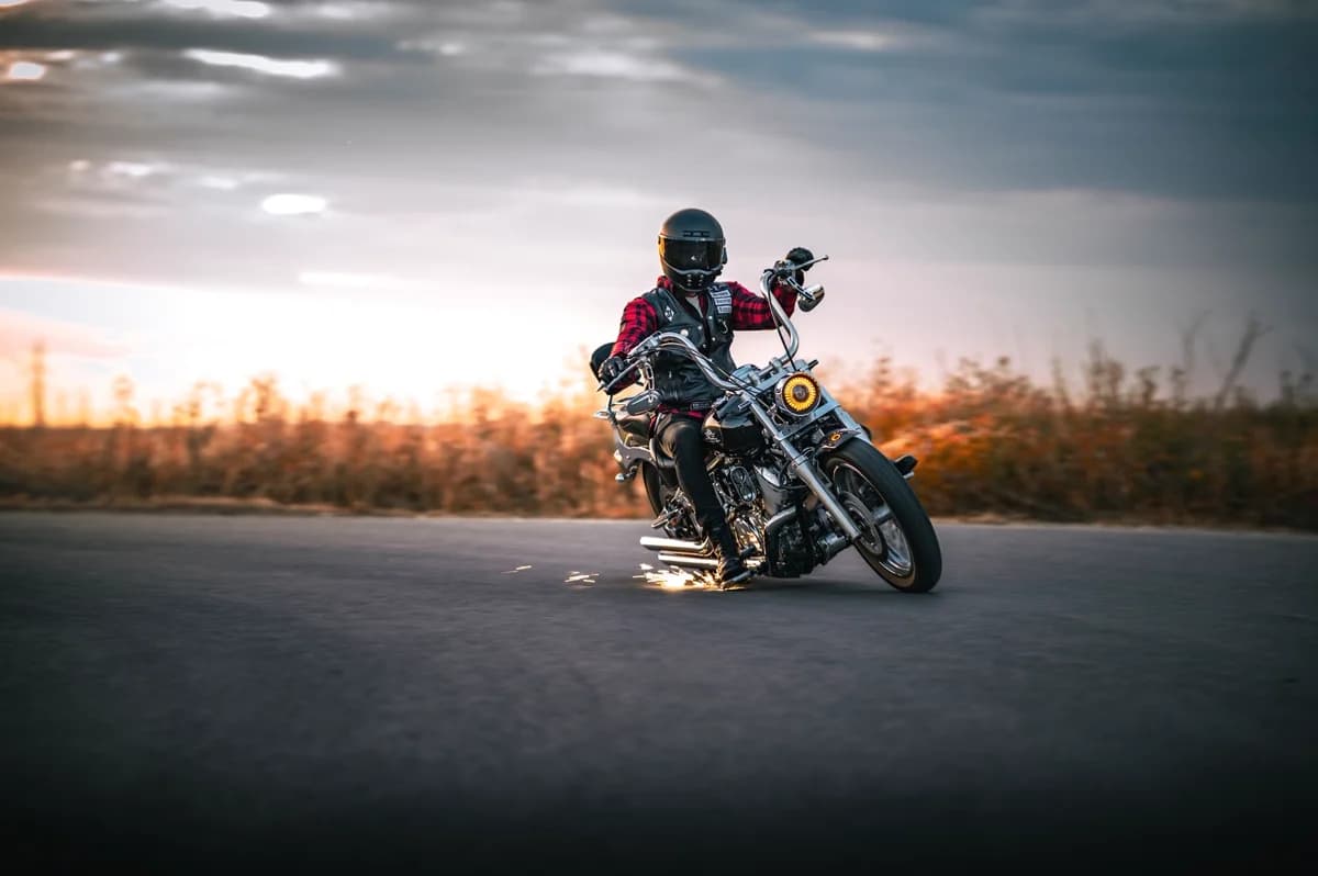 Piloto inclinando a moto em curva ao pôr do sol