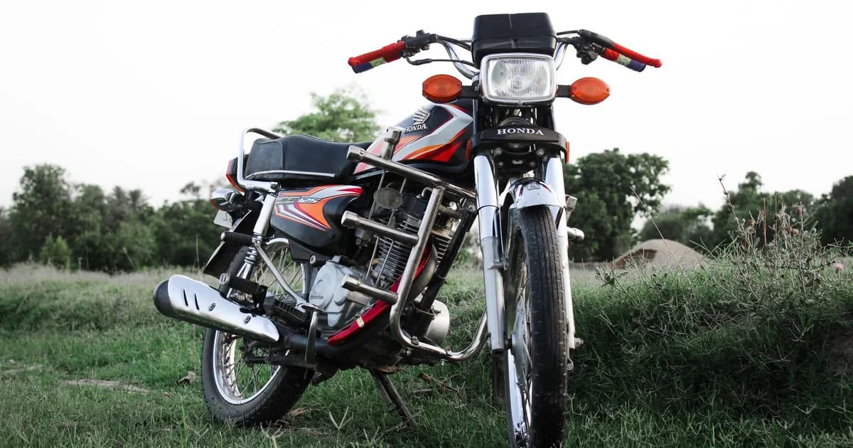 Moto de entrada estilo CG estacionada em área aberta, vista de frente em ângulo baixo