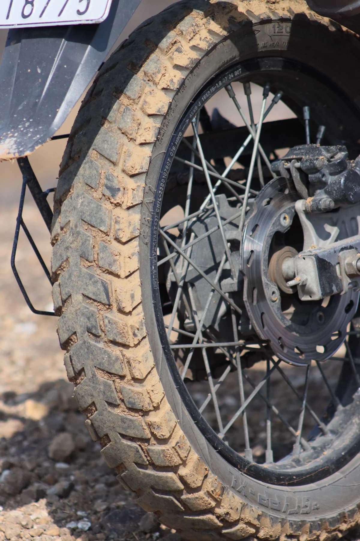 Roda de moto off-road com barro em close, mostrando desgaste severo