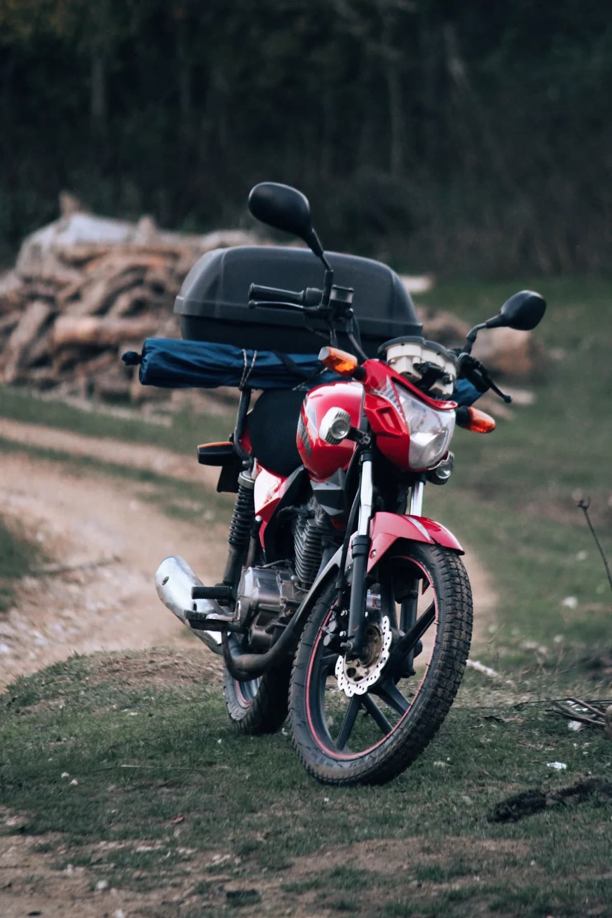 Moto vermelha em caminho de terra em meio à mata