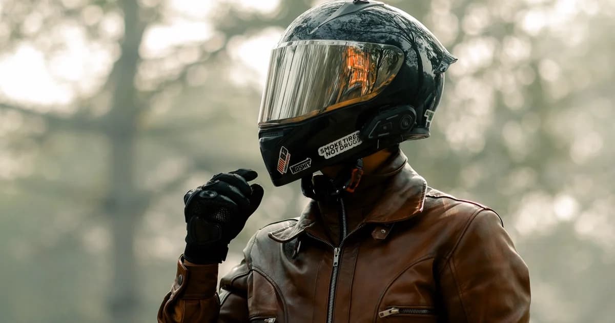 Motociclista de capacete em estrada de serra com neblina