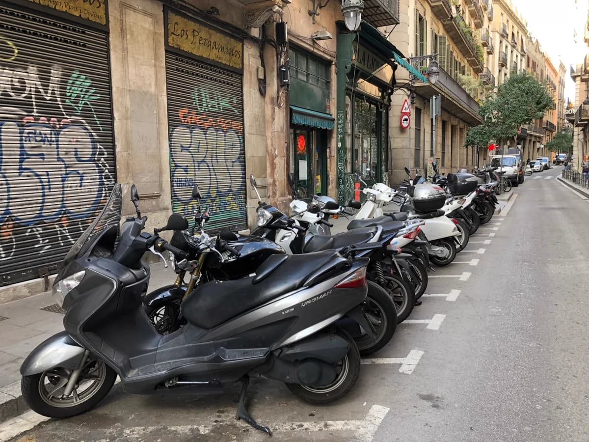 Motos enfileiradas ao lado de muro grafitado